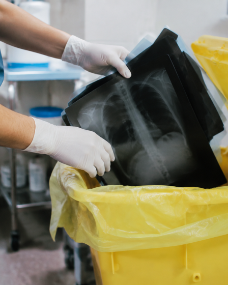Mains inserant radiographies dans conteneur de dechets medicaux